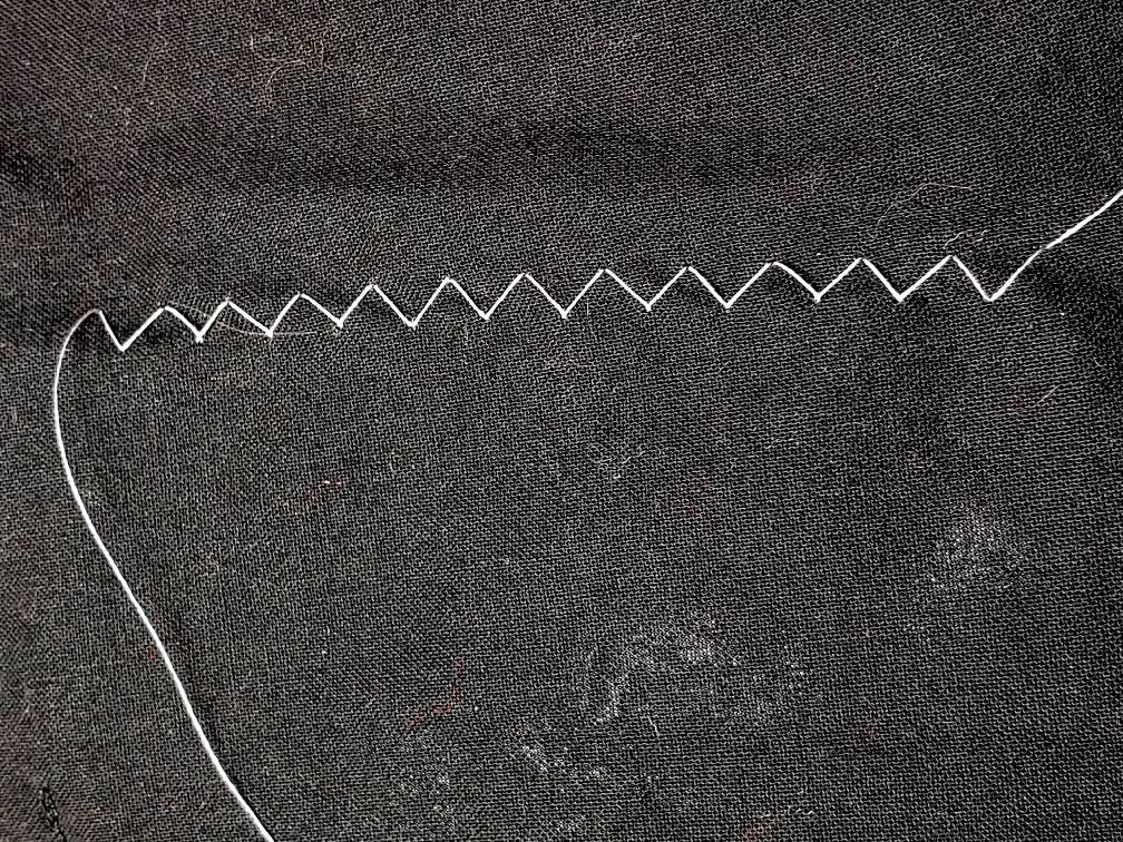 A white zigzag stitch on black fabric