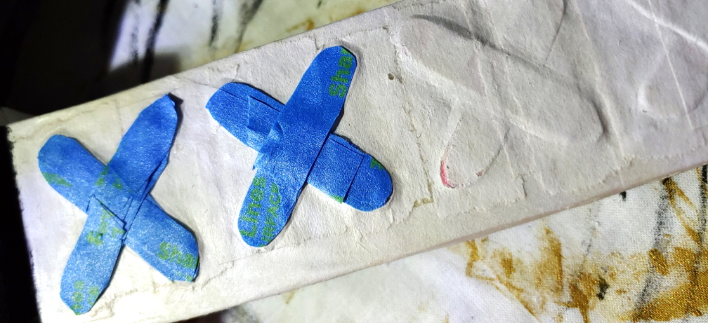 Masking off the laces to paint the rest of the base. Blue painter's tape covers the raised details of X-shaped laces.
