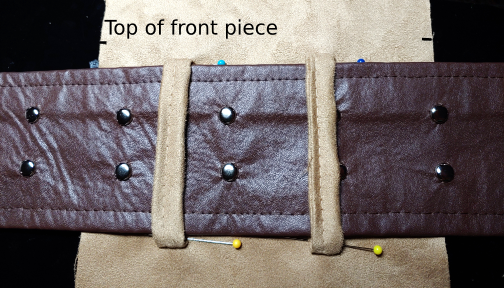 Belt loops pinned around the belt with a little bit of wiggle room. A dark brown belt is threaded through beige belt loops. At the top are small tick marks labeled "top of front piece".