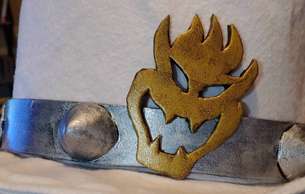 Foam details for wedding Bowser hot glued to a felt hat. A gold Bowser face sits on top of a silver band with sculpted spikes.