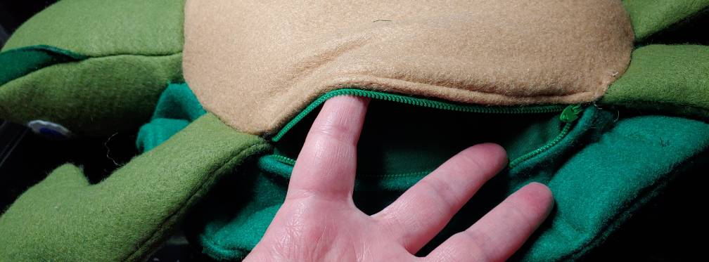 Zipper pocket in the turtle plush, hidden underneath the shell and opened with my fingers to show the inside.